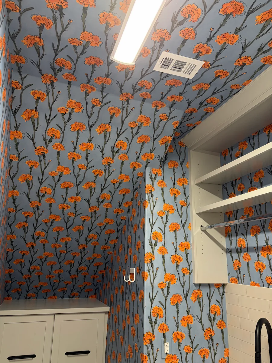 Orange floral wallpaper covering the walls and sloped ceiling of a closet